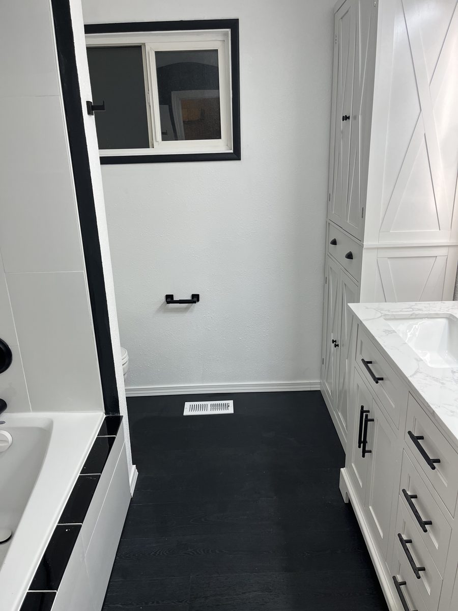 White bathroom cabinetry with quartz top and black tile floor