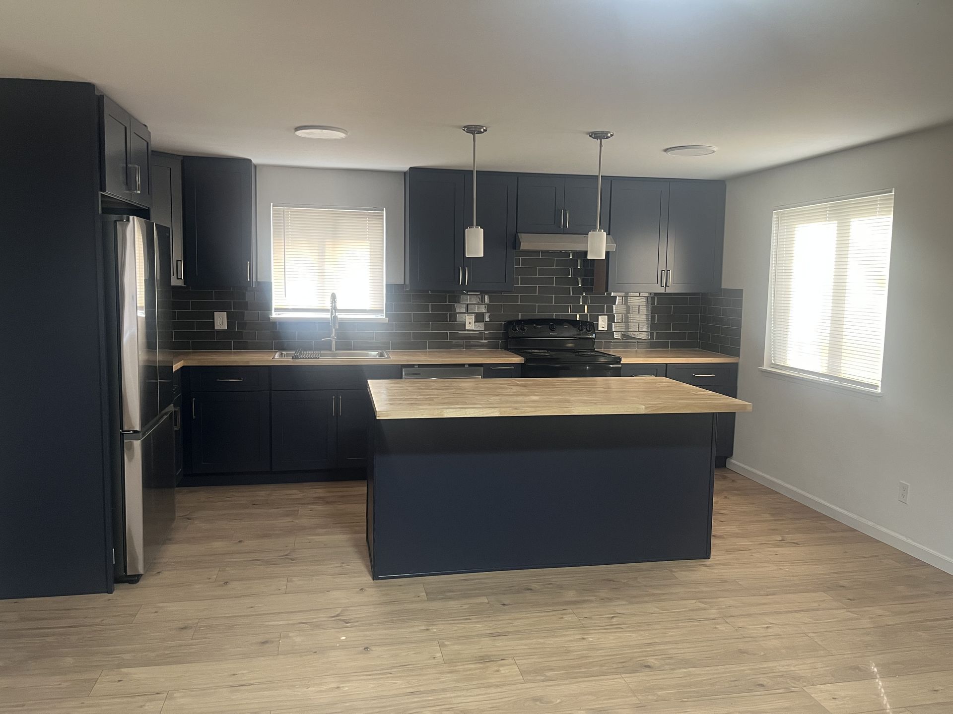 Navy kitchen with butcher-block island, remodeled by M & Sons
