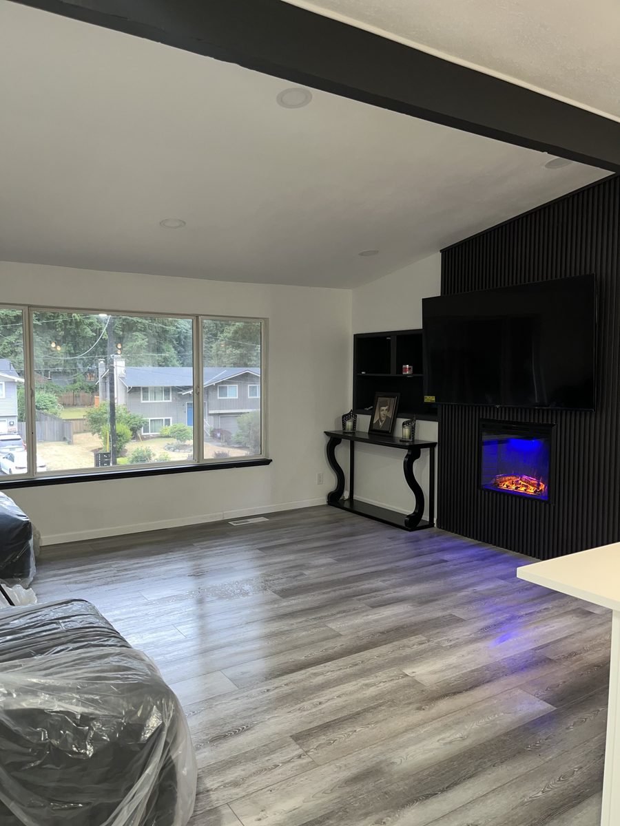 Living room with black slat media wall, electric fireplace and new flooring